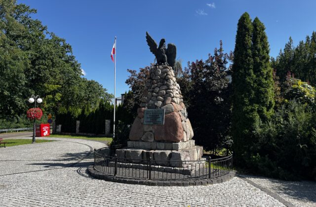 Kamienny pomnik Legionów Polskich w Białobrzegach otoczony ozdobnym ogrodzeniem