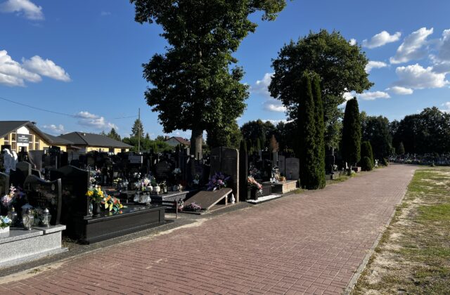 Alejka z czerwonej kostki między nagrobkami cmentarza parafialnego w Nieporęcie