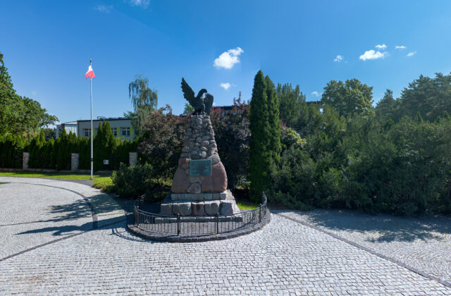 Pomnik Oficerów Legionów Polskich w Białobrzegach z orłem na szczycie, na wybrukowanym placu