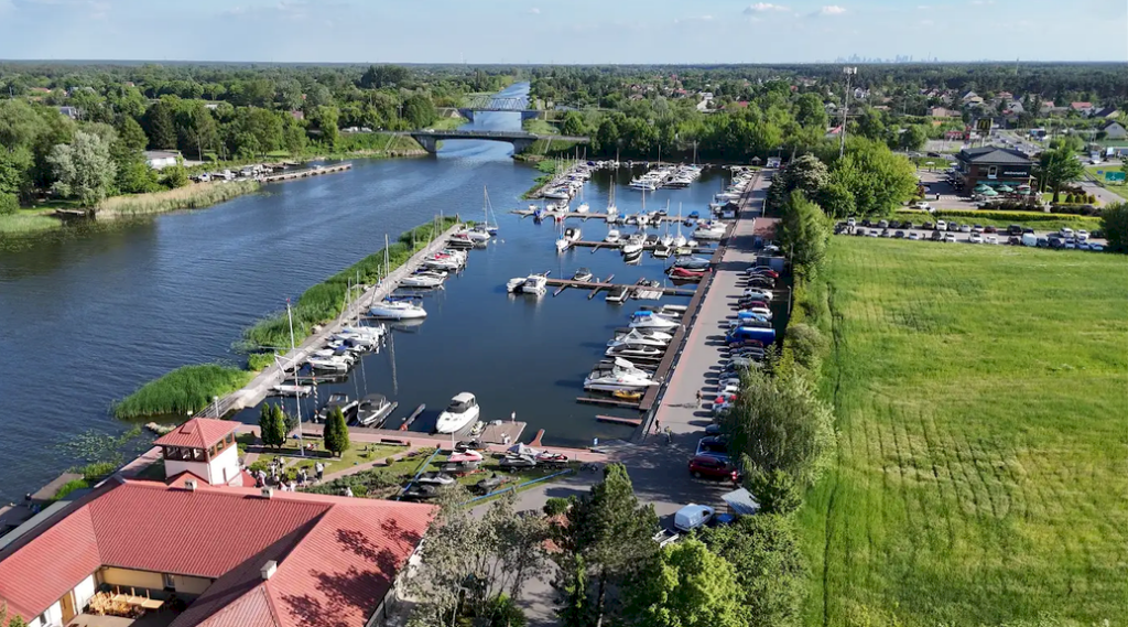 Port jachtowy „Wodnik” z lotu ptaka – łodzie przy pomostach na kanale i budynki portu z czerwonymi dachami