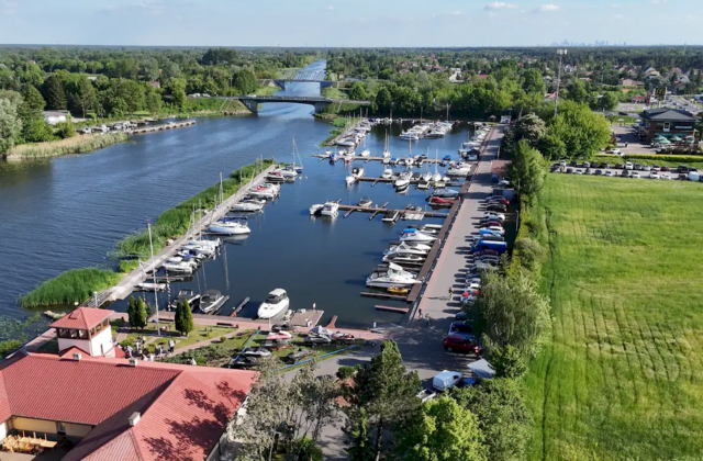 Port jachtowy „Wodnik” z lotu ptaka – łodzie przy pomostach na kanale i budynki portu z czerwonymi dachami