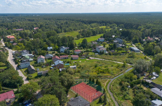 Rynia z drona – zabudowa wśród lasów i kort sportowy