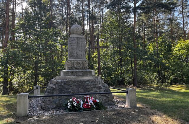 Pomnik Strzelców Kaniowskich w Wólce Radzymińskiej – cokół z kamienia polnego za niskim ogrodzeniem