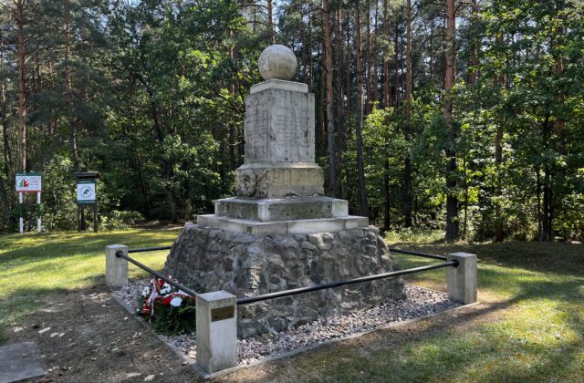 Pomnik Strzelców Kaniowskich na leśnej polanie, z boku tablice informacyjne